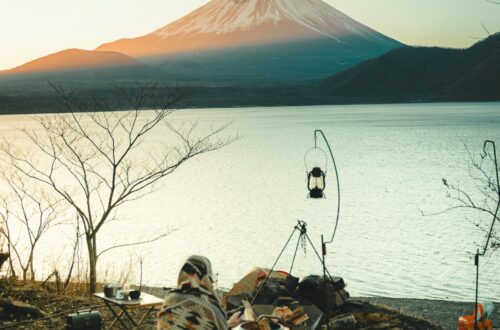 Person sitting by the lake camping with basic survival skills