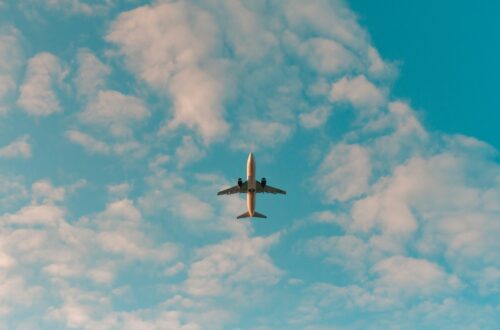 Plane climbing in the sky with scattered clouds and blue sky