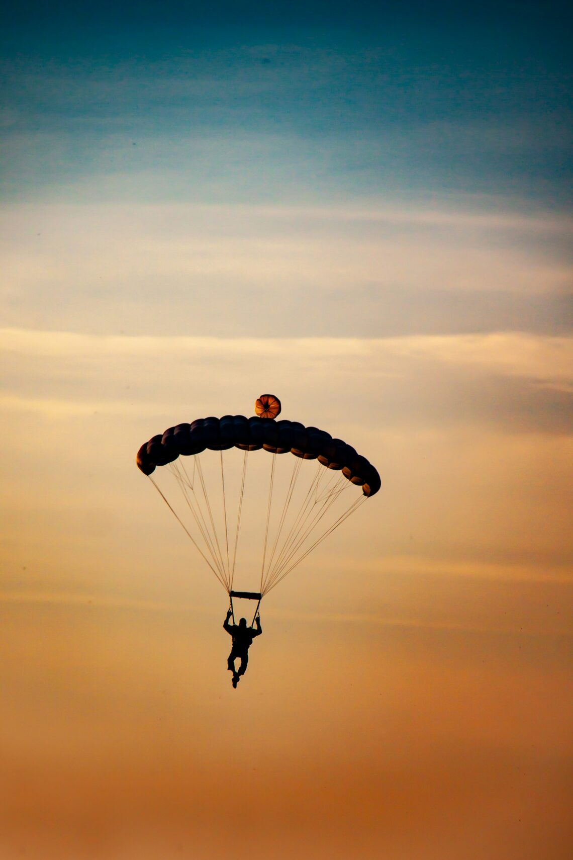 A parachuter in full flight with blue and orange skys