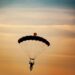 A parachuter in full flight with blue and orange skys
