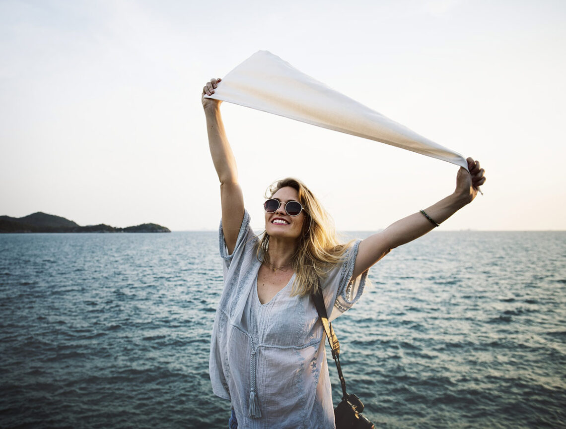 Girl with a scarf on the beach smiling and happy
