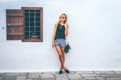 Lady against a white wall standing relaxed deep in thought