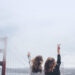 Two girls showing the peace sign with ther hand looking at the san Francisco golden gate bridge