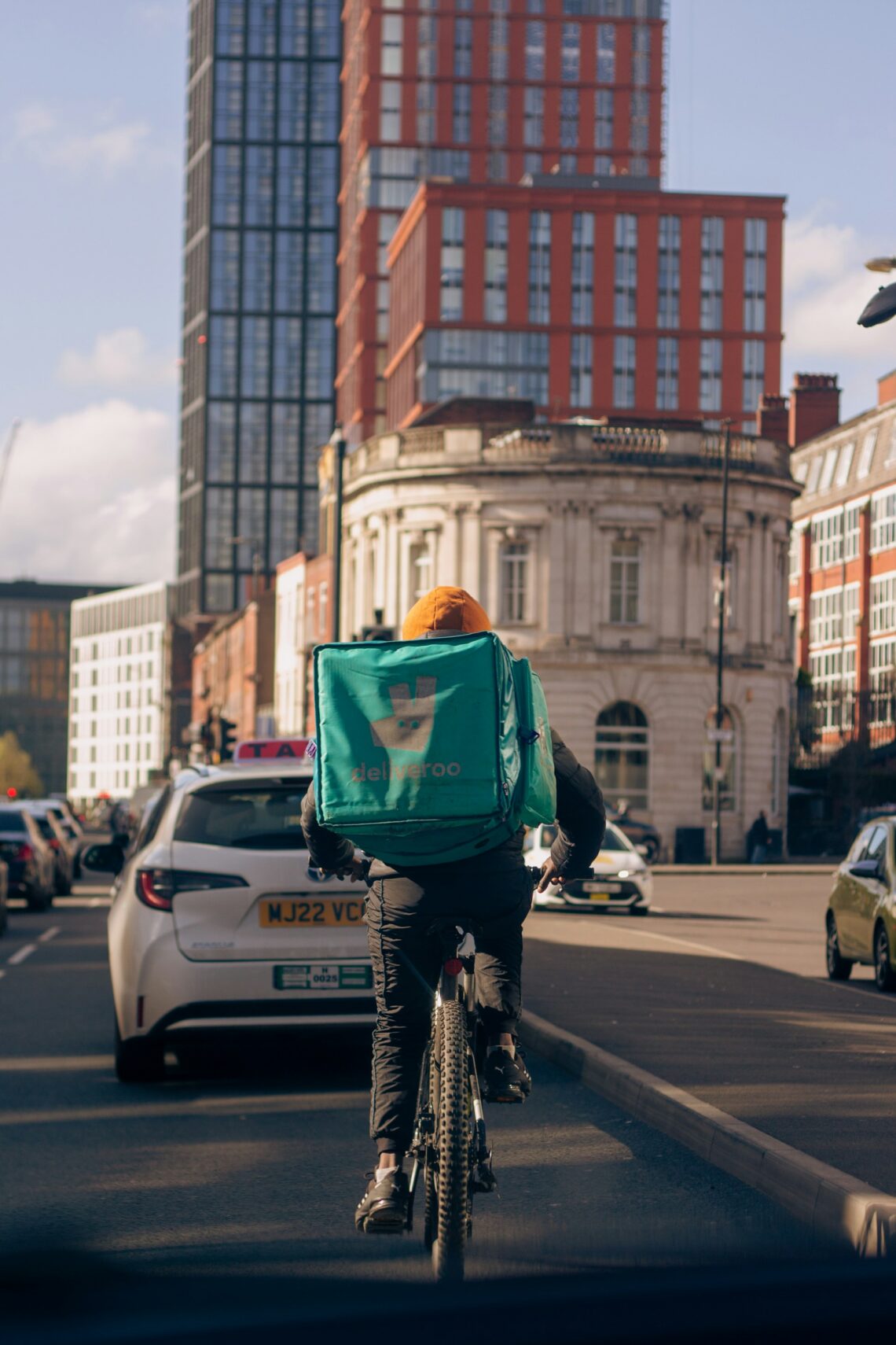Delivery rider in city traffic with building and cars surrounding