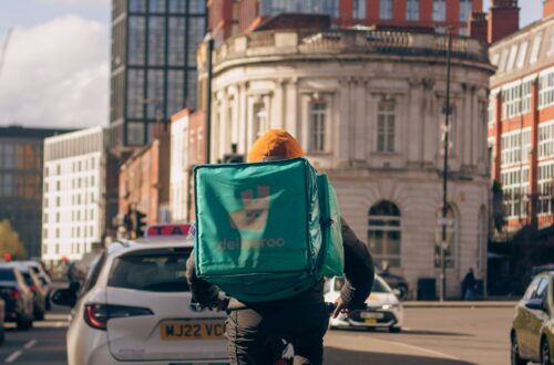 Delivery rider in city traffic with building and cars surrounding