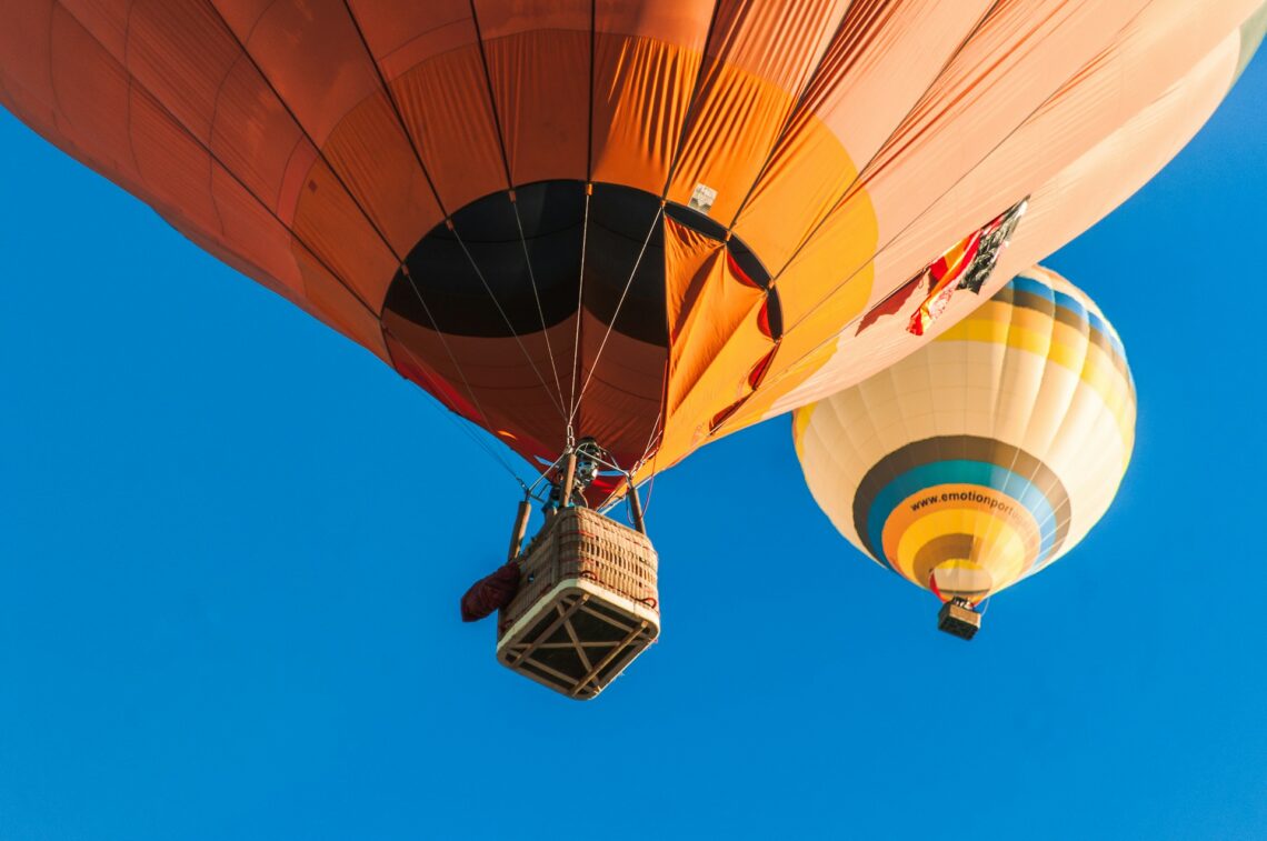 Hot air balloons flying with the basket visible in the first balloon aloft
