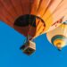 Hot air balloons flying with the basket visible in the first balloon aloft