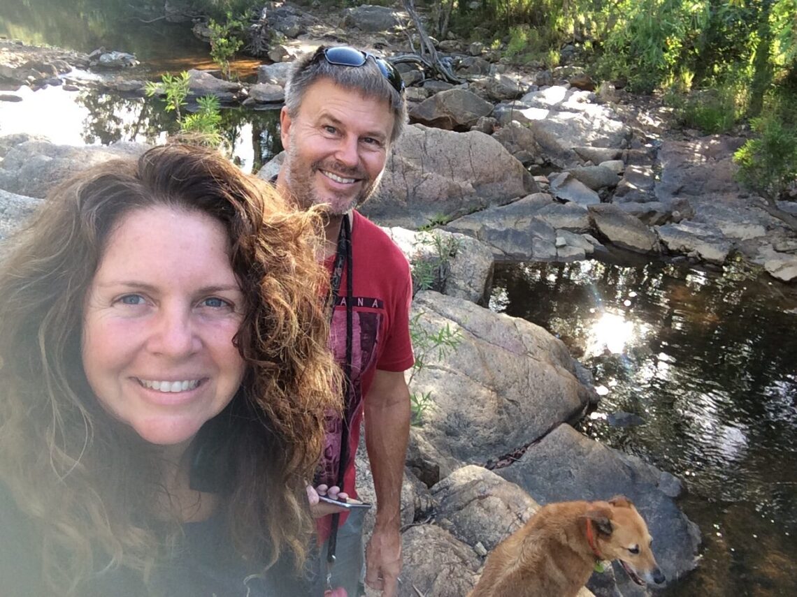 Two people by the creek with stones water with a dog