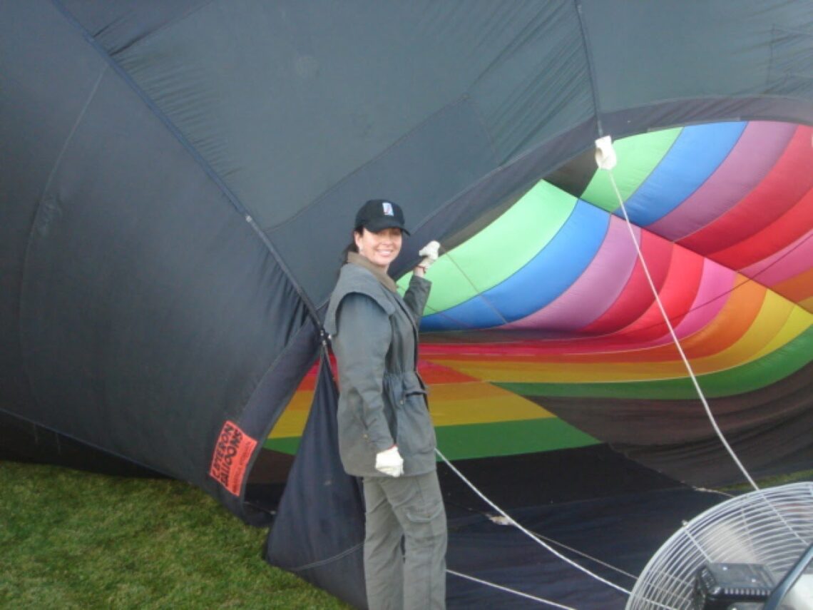 Girl pilot next to a hot air balloon inflating