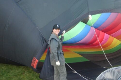 Girl pilot next to a hot air balloon inflating