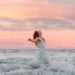 Woman Splashing through waves with beautiful sunrise arms out like letting go or freedom